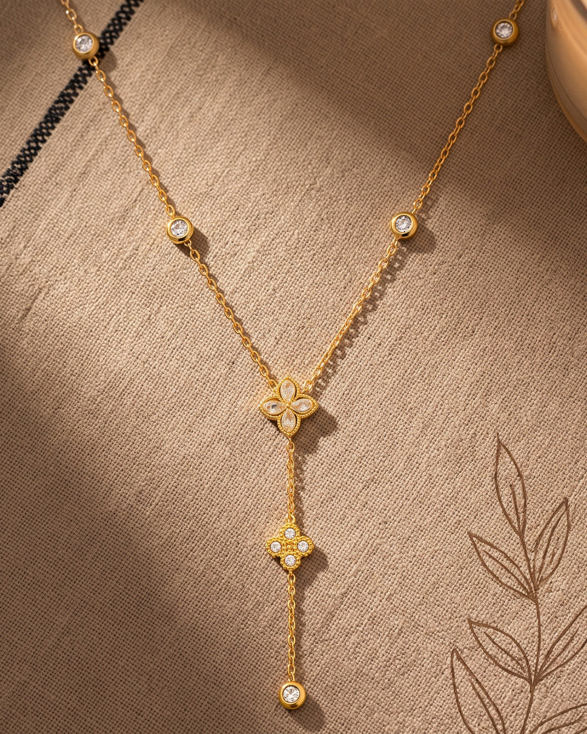 Flower Lariat Necklace: laid flat on warm linen, gold tone